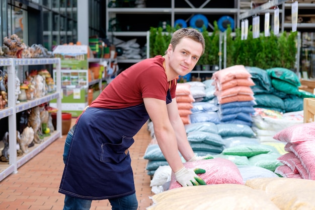 Joven trabajador en invernadero de mercado de plantas en el trabajo