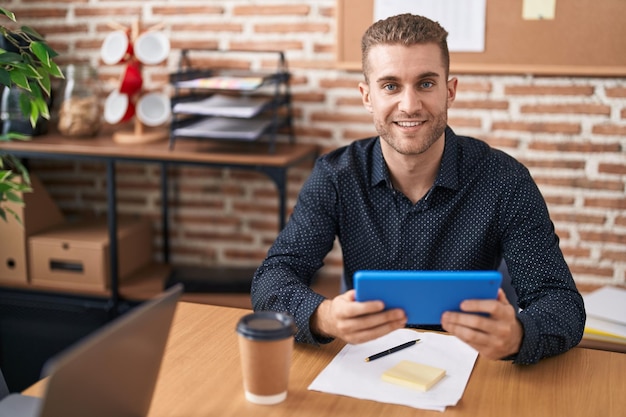 Joven trabajador de negocios caucásico usando panel táctil trabajando en la oficina