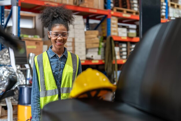 Foto joven trabajadora afroamericana conductora de montacargas relajándose después del trabajo en el almacén de la fábrica