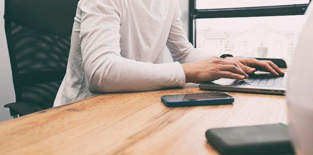 Joven trabajando en una computadora portátil mientras está sentado en el espacio de coworking Concepto independiente