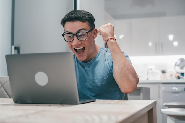 Un joven trabajando y ganando algo con una laptop en casa Adolescente feliz y eufórico celebrando buenas noticias y divirtiéndose disfrutandoxA