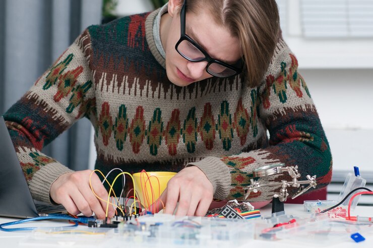 Foto joven trabajando intensamente con piezas electrónicas.