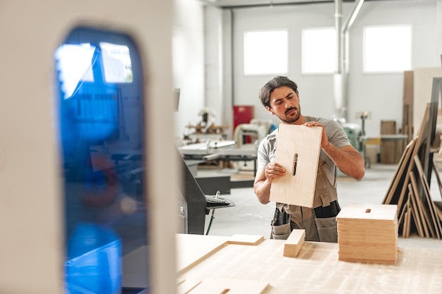 Foto joven trabajando en madera en una fábrica de carpintería de cerca