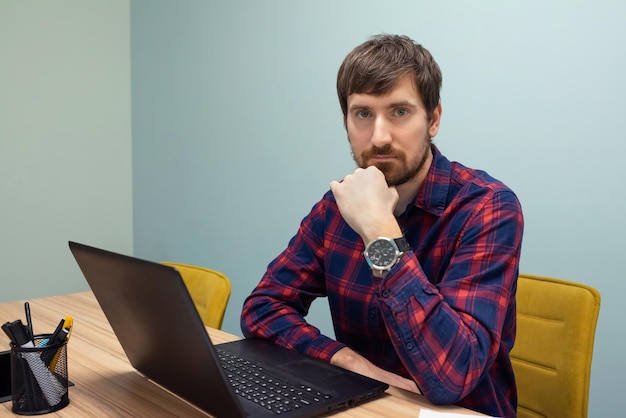 Joven trabajando en la oficina en una computadora portátil en la mesa de la oficina