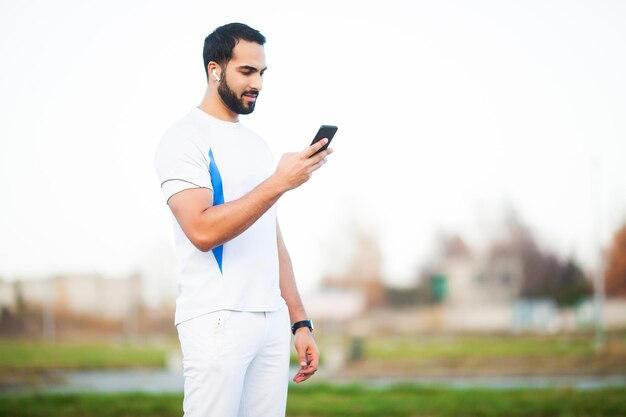 Joven trabajando en el parque de la ciudad y usando su teléfono móvil