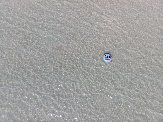 Joven en traje de baño relajante en un anillo de goma en el mar con sus vacaciones de verano