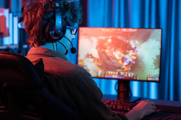 Joven transmisor de juegos jugando a luchar contra Moba con auriculares y micrófono Gusher