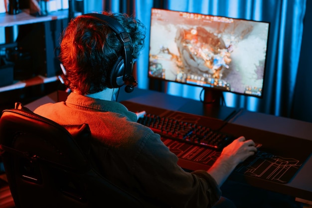 Joven transmisor de juegos jugando a luchar contra Moba con auriculares y micrófono Gusher