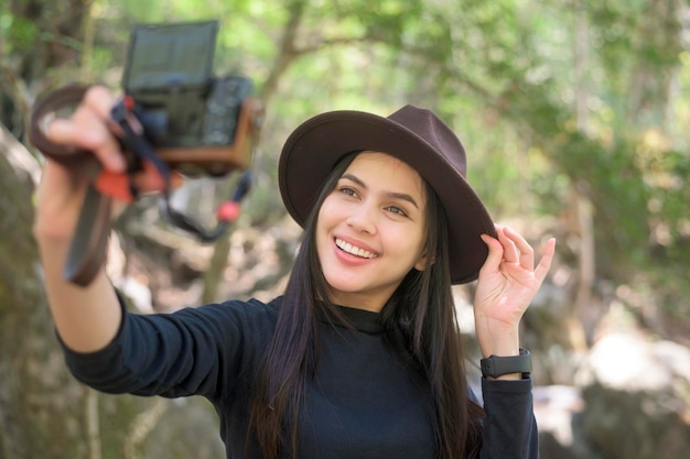 Una joven trekker tomando selfie con cámara en el bosque vacaciones y concepto de viaje