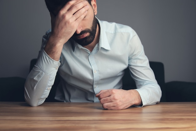 Foto joven y triste hombre de negocios de la mano en la cabeza