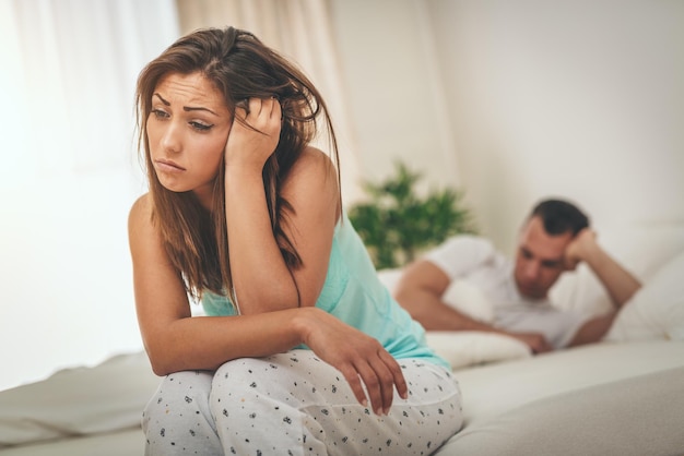 Una joven triste se siente estresada después de una pelea con su esposo, está sentada al borde de la cama llorando.