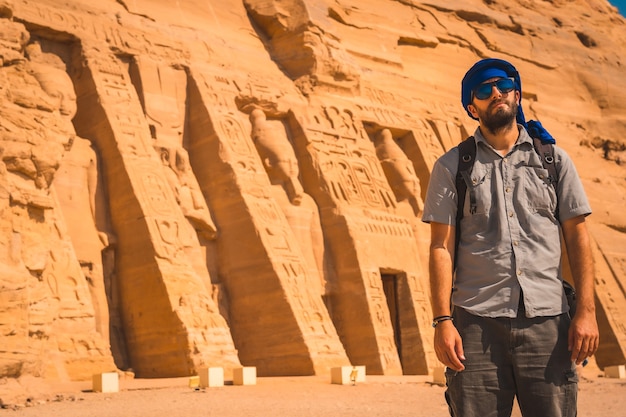 Un joven con un turbante azul y gafas de sol en el templo de Nefertari, cerca de Abu Simbel, en el sur de Egipto, en Nubia, junto al lago Nasser. Templo del faraón Ramsés II, estilo de vida de viaje