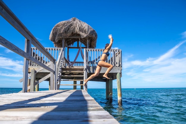 Una joven turista arrojándose al Mar Caribe en la isla de Roatán desde un muelle de madera Honduras