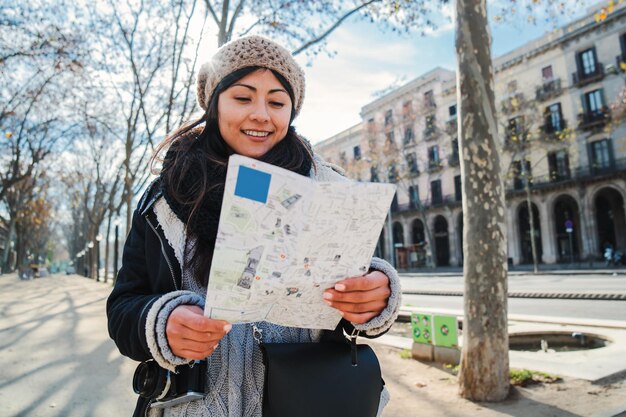 Una joven turista asiática buscando direcciones en un mapa de papel visitando una ciudad europea