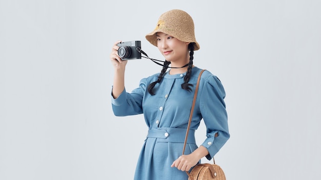 Una joven turista asiática emocionada caminando mientras toma una foto con una cámara de fondo blanco