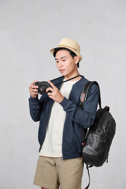 Joven turista asiático sonriendo feliz usando un teléfono inteligente vintage