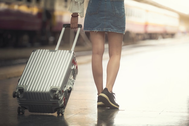 Joven turista caminando equipaje remolque caminando en la estación de tren