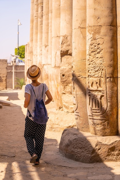 Un joven turista con una camiseta blanca y un sombrero visitando el templo Templo de Luxor Egipto