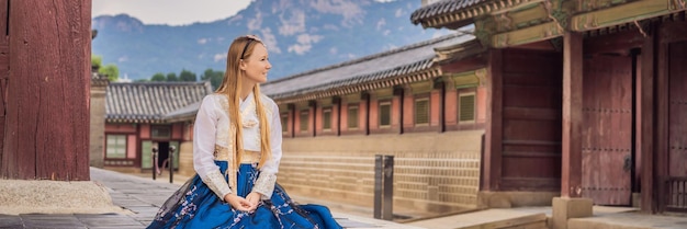 Joven turista caucásica en hanbok vestido nacional coreano Viaje a Corea concepto vestimenta nacional coreana Entretenimiento para turistas probando ropa nacional coreana BANER FORMATO LARGO