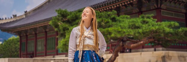 Joven turista caucásica con vestido nacional coreano hanbok Concepto de viaje a Corea Ropa nacional coreana Entretenimiento para turistas probándose ropa nacional coreana BANNER FORMATO LARGO