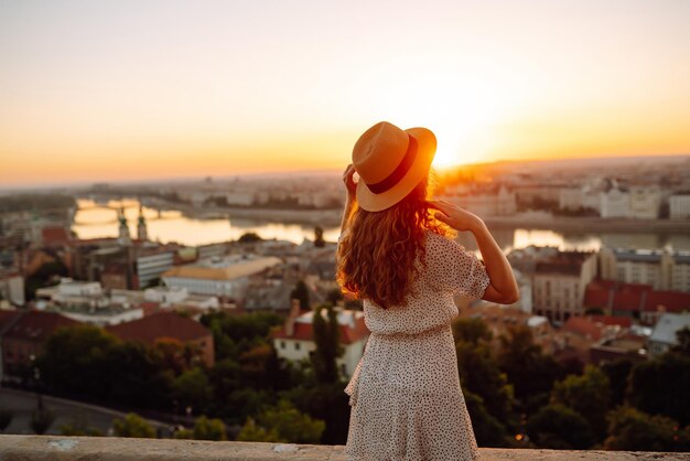 Joven turista disfruta de la vista de la ciudad al atardecer vista posterior Estilo de vida viajes naturaleza vida activa