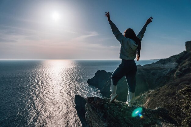 Una joven turista disfrutando de la puesta de sol sobre el mar paisaje de montaña mientras está sentado yoga para mujeres al aire libre