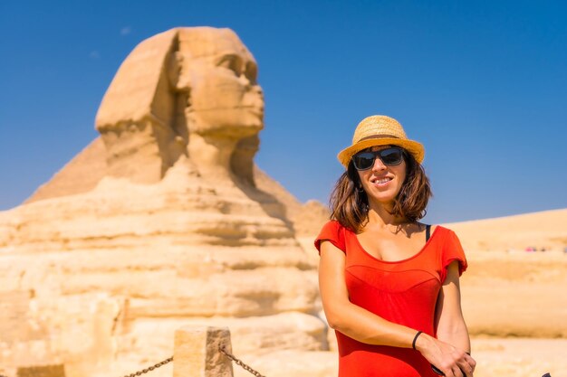 Un joven turista en la Gran Esfinge de Giza vestido de rojo y con sombrero