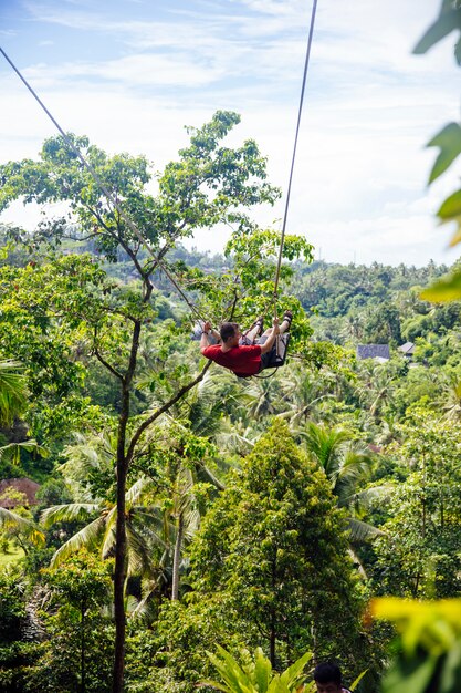 Joven turista masculino balanceándose en el acantilado en la selva