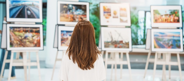 Joven turista mirando exposición de galería Fotografía de arte y concepto de museo