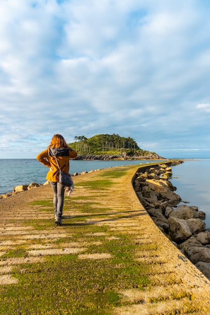 Un joven turista en la pasarela para ir a la isla de San Nicolás durante la marea baja desde la playa de Isuntza en Lekeitio, País Vasco