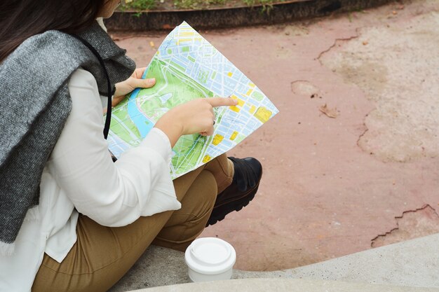 Joven turista pensativa en ropa de abrigo con mapa