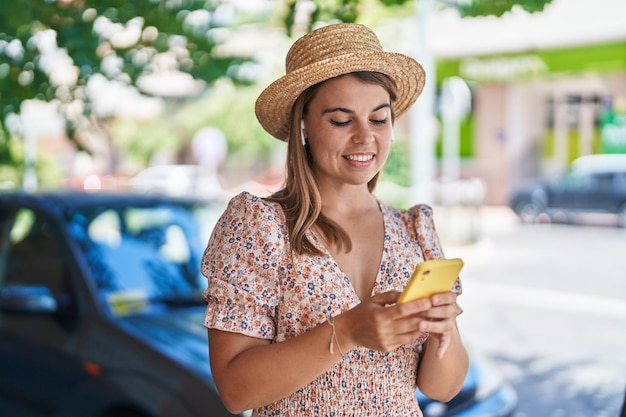 Joven turista con sombrero de verano escuchando música en la calle