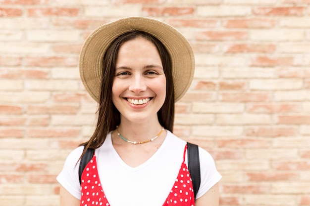 Foto joven turista sonriendo mientras mira a la cámara delante de la pared