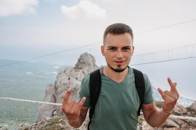 Un joven turista subió a la cima del acantilado con una mochila El concepto de vida activa y senderismo