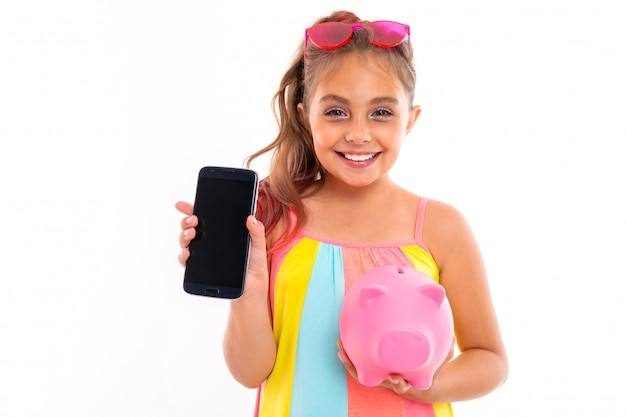 Joven turista con un teléfono con una maqueta rosa hucha en una pared blanca