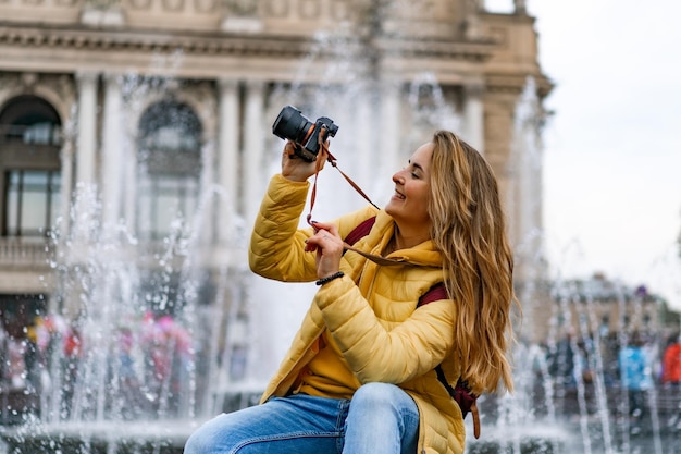 Foto joven turista toma fotografías en un viaje. una mujer con una cámara en las manos camina por la ciudad.