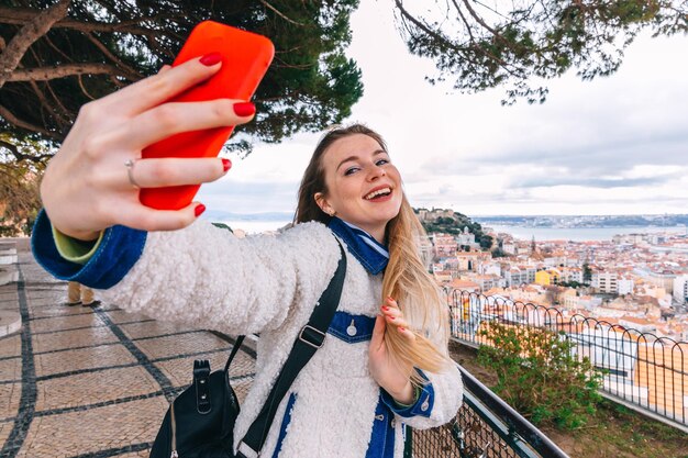 Foto joven turista tomando una foto selfie en el hermoso paisaje urbano de fondo en el casco antiguo durante un día soleado en lisboa, portugal