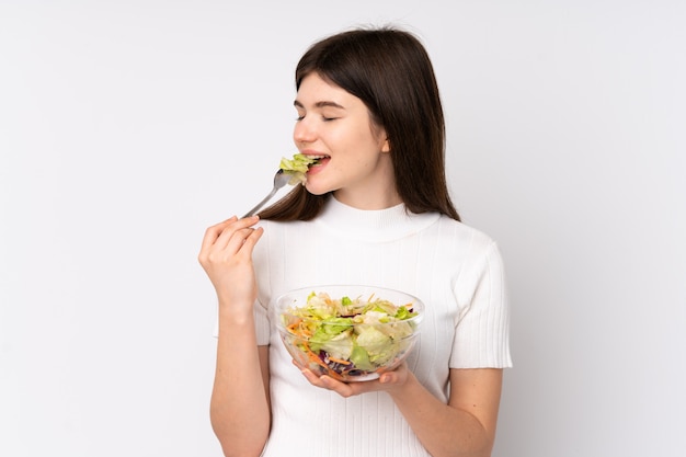 Joven ucraniana adolescente sosteniendo una ensalada sobre pared blanca