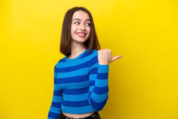 Joven ucraniana aislada de fondo amarillo apuntando hacia un lado para presentar un producto