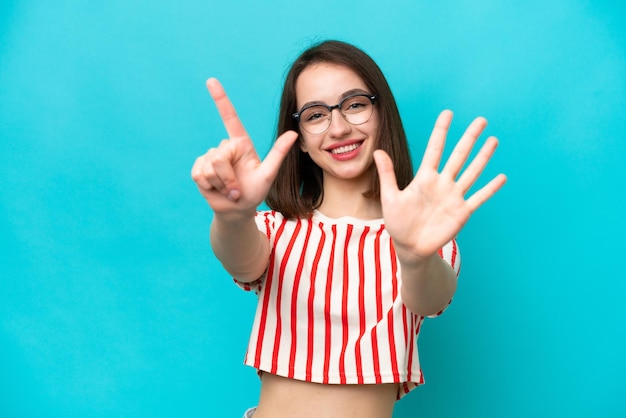 Joven ucraniana aislada de fondo azul contando siete con los dedos