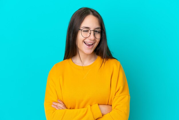 Joven ucraniana aislada de fondo azul con gafas y expresión feliz