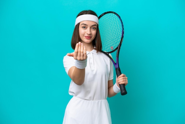 Joven ucraniana aislada de fondo azul jugando al tenis y haciendo el gesto de venir