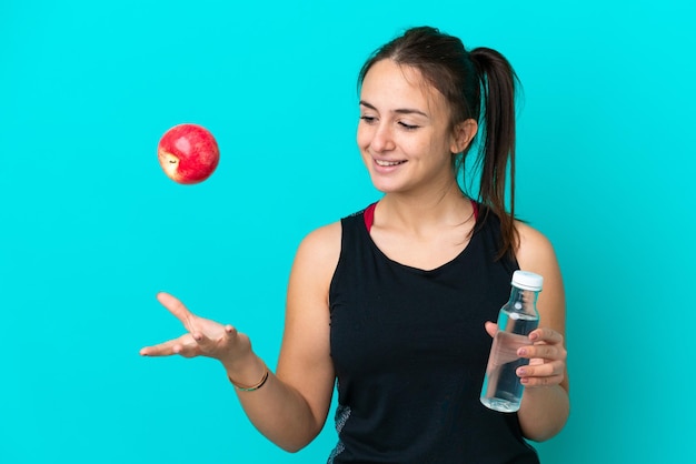 Joven ucraniana aislada de fondo azul con una manzana y una botella de agua