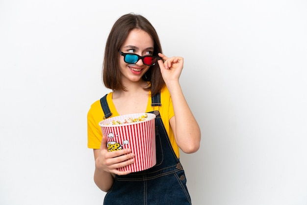 Joven ucraniana aislada de fondo blanco con gafas 3d y sosteniendo un gran cubo de palomitas de maíz