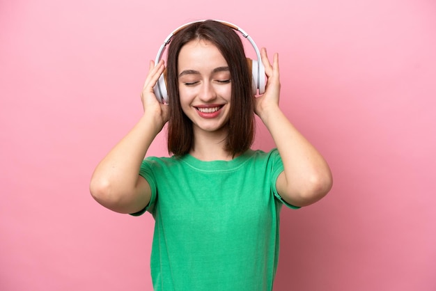 Joven ucraniana aislada de fondo rosa escuchando música