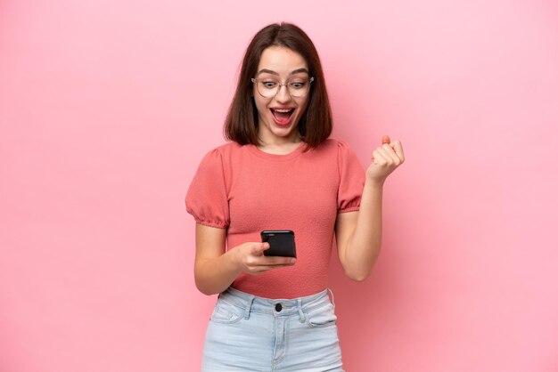 Joven ucraniana aislada de fondo rosa sorprendida y enviando un mensaje