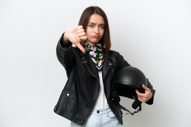 Joven ucraniana con casco de motocicleta aislado de fondo blanco mostrando el pulgar hacia abajo con expresión negativa