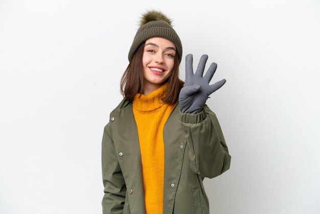 Joven ucraniana con chaqueta de invierno aislada de fondo blanco feliz y contando cuatro con los dedos