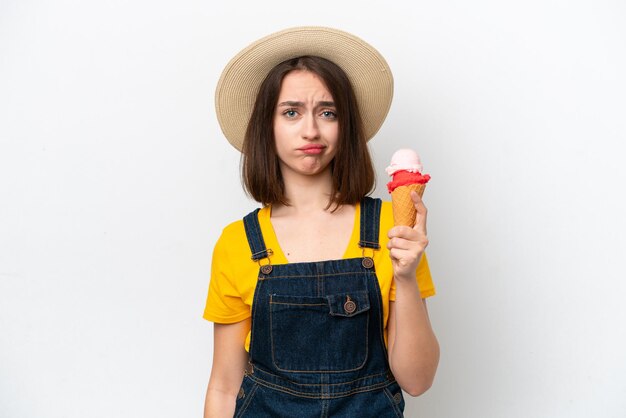 Joven ucraniana con un helado de cucurucho aislado de fondo blanco con expresión triste