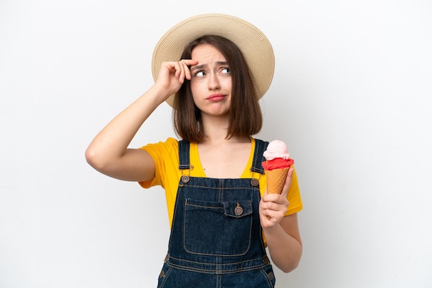 Joven ucraniana con un helado de cucurucho aislado de fondo blanco que tiene dudas y con una expresión facial confusa